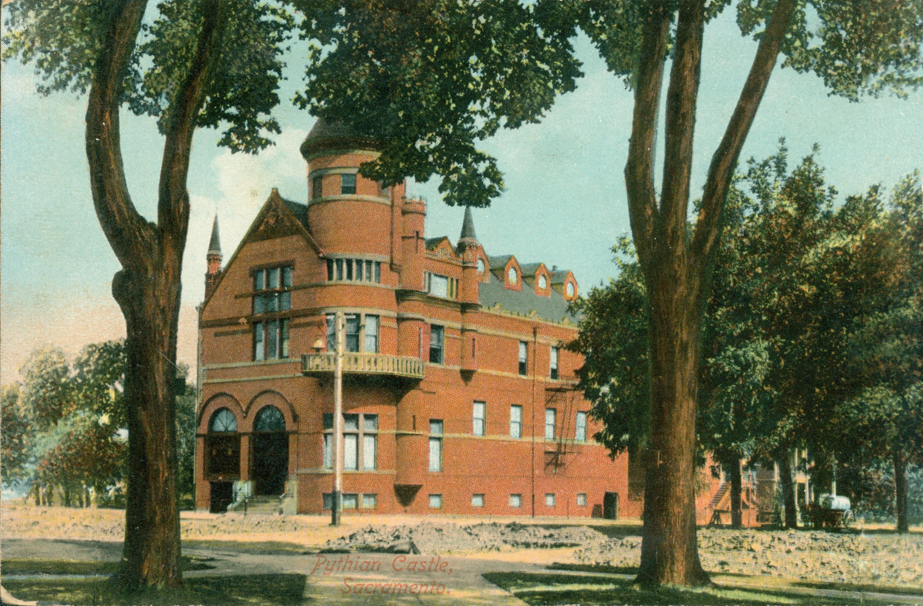 This postcard shows the Pythian Castle, a red brick building, framed by trees.